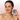 Hand holding Bubblux Facial Vibrating Cleanser for deep pore cleansing and gentle facial exfoliation, shown against a soft pink background.